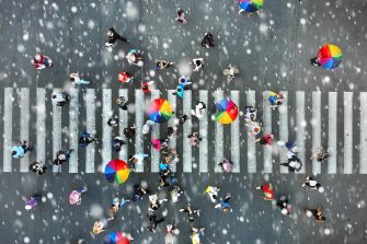 Aerial. People crowd on a pedestrian crossing crosswalk when it's rain. View above. Centre for Social Research in Health