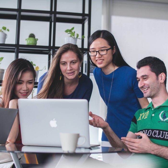 Four people looking at the laptop Four people looking at the laptop