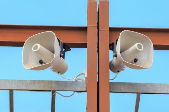Two big white loudspeakers on the brown construction