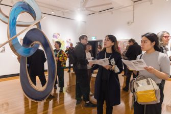 Patrons in an art gallery look at the exhibition of Tim Olsen Drawing Prize 2023