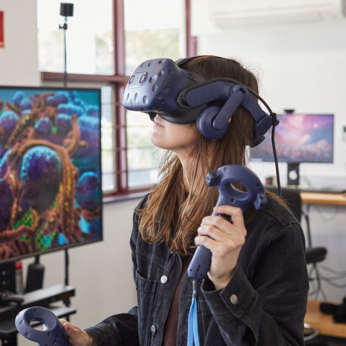 Student using virtual reality headset and controls in 3D Visualisation Aesthetics Lab.