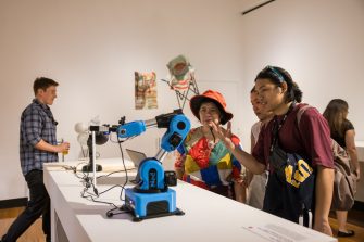 Two people standing in a gallery space, looking at the A&D Annual 2023 exhibition. 