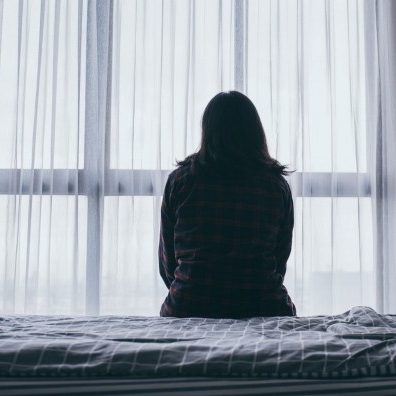 Woman sitting alone in room looking at window