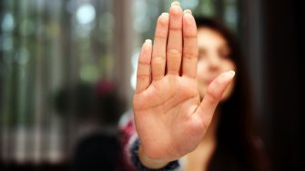 Woman with her hand extended signaling to stop (only her hand is in focus)