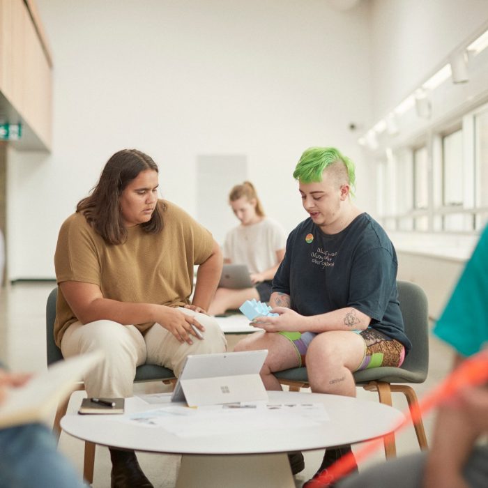 Art and design students discussing work inside the Red Center build enviroment study space.