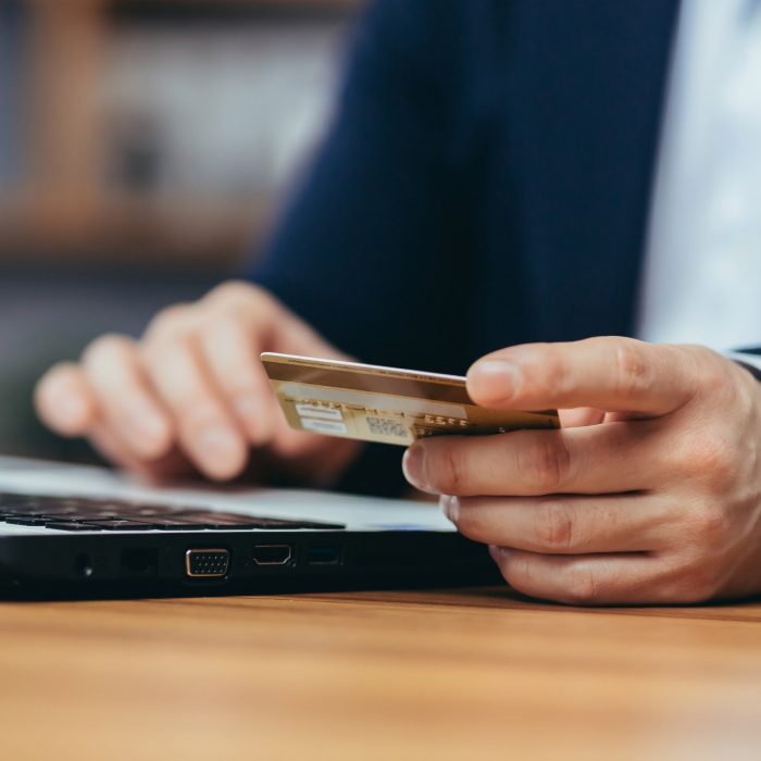 Close-up photo of businessman making online shopping in online store, man using laptop, man holding credit bank card