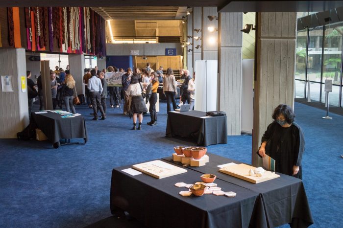 Guests and team members mingling around artifacts and socialising in foyer of John Clancy Auditorium UNSW Sydney