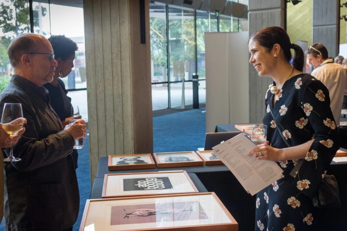 Guests and team members mingling around artifacts and socialising in foyer of John Clancy Auditorium UNSW Sydney 