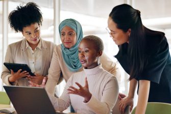 Diversity, corporate and women with laptop, talking and planning budget, fintech and system update in modern office. Team, leader and group online reading, finance and.accounting process on computer.