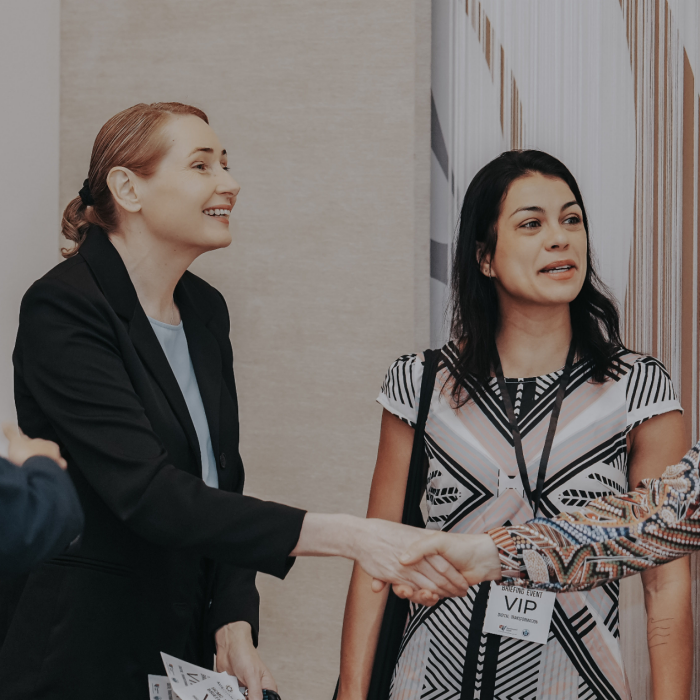 Two ladies gretting a guest at a UNOVA event