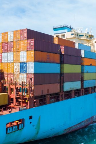 Stern of large cargo ship import export container box on the ocean sea on blue sky back ground concept transportation logistic and service to customer and supply change, webinar banner