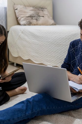 One man, young boy is tired of doing homework, sitting at the table, using laptop.