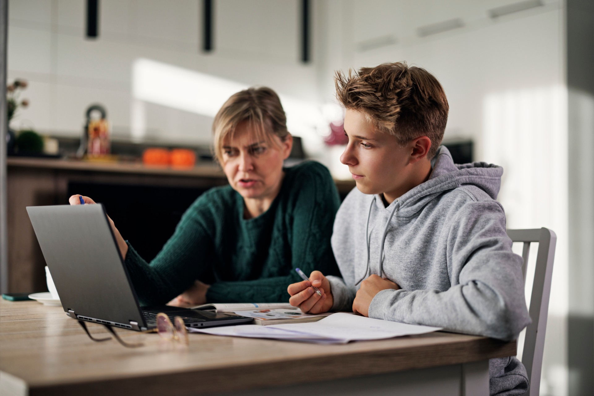 Mother and teenage boy doing some homework together. Mother is helping son with his lessons.Shot with Canon R5