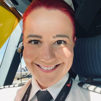 Close-up of Lizzie smiling at camera while sitting in cockpit of plane