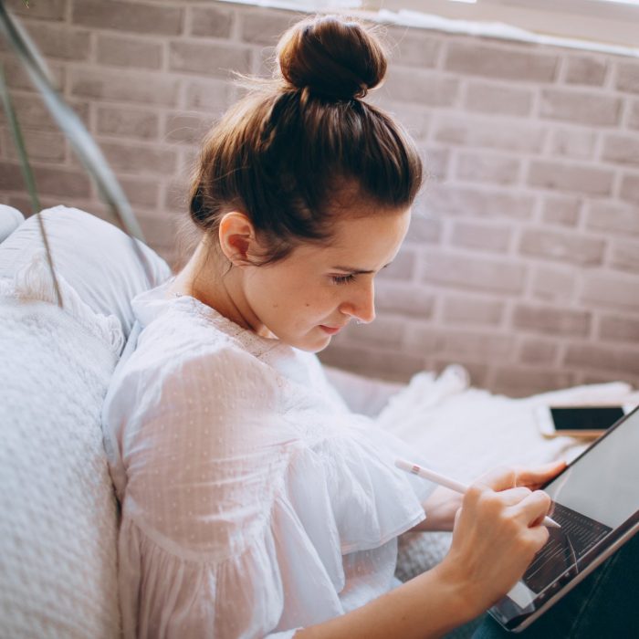 Woman in white shirt holding black and silver laptop computer