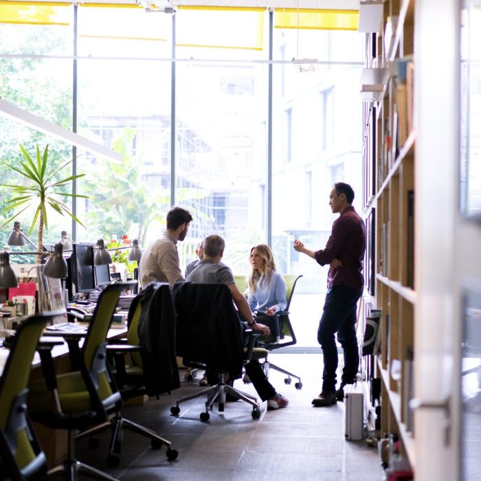 Multi-ethnic business people discussing in office. Male and female professionals are working together at workplace. They are wearing smart casuals.