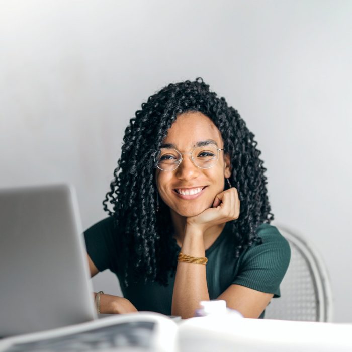 Women smiling at the camera in front of her laptop