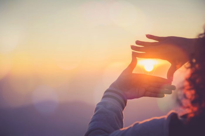 The woman making frame round the sun with her hands in sunrise,Future planning idea concept.