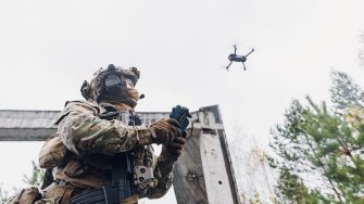 Military soldier controls drone for reconnaissance operation of enemy positions. Concept using quadrocopters in smart war.