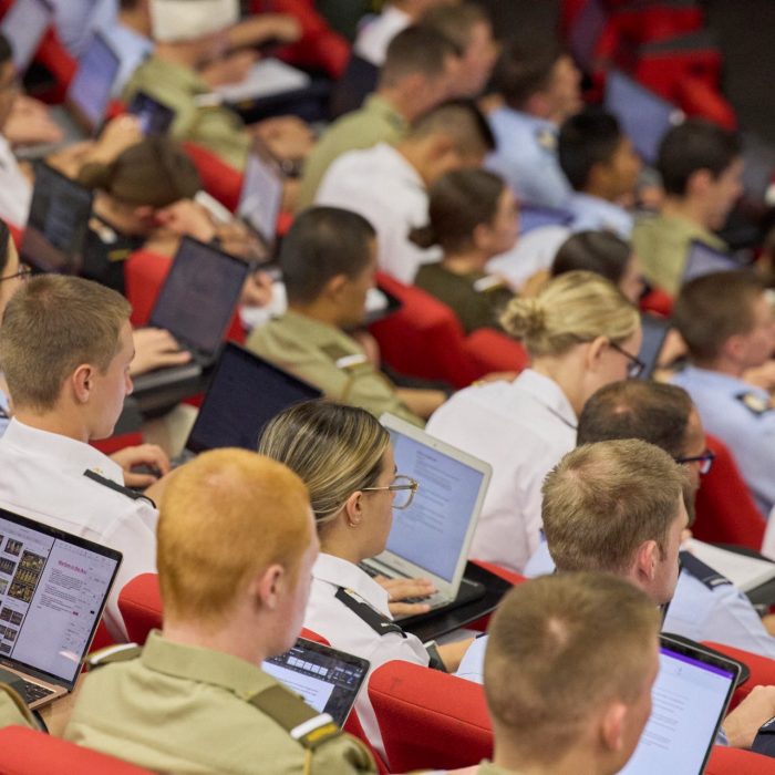 Students in a lecture theatre take notes on their laptops