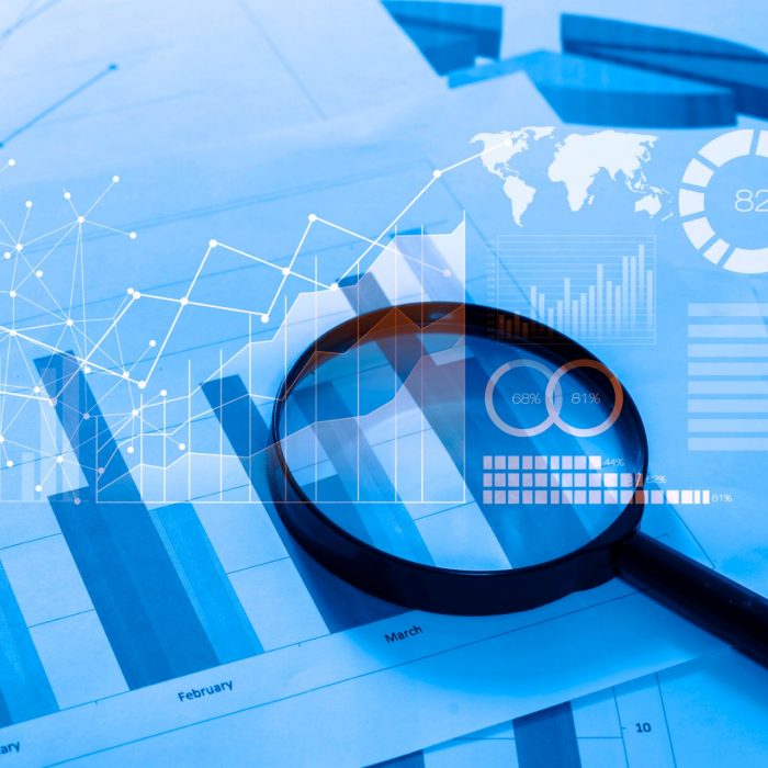 Magnifying glass and documents with analytics data lying on table,selective focus