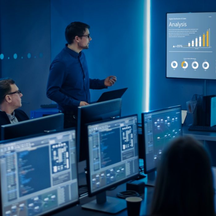 Team of Professional IT Developers Have a Meeting, Speaker Shows Growth Data with Graphs, Charts, Software UI. Shown on TV. Concept: Software UI Development, Deep Learning, Graphs, Charts.