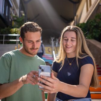 Two students looking at a phone with the Basser Steps in the background