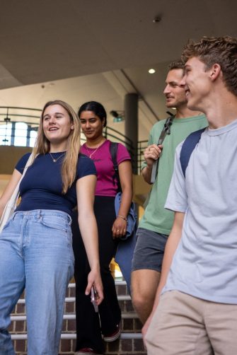 A group of students chatting while walking down a staircase in front of the Quad Food Court