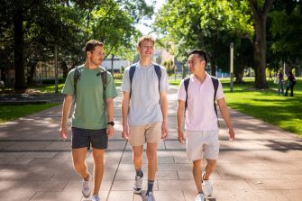 Three students chatting while walking on the Kensington Campus main walkway, University Mall