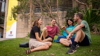 Four students chatting while sitting on Eleanora Kopalinsky Lawn on Kensington Campus