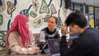 Students with their laptops sitting at an outdoor table on Paddington Campus