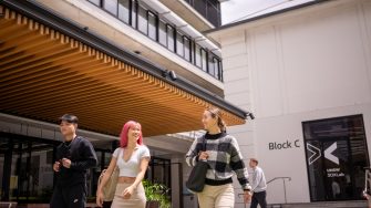 Three students chatting while walking outdoors on Paddington Campus