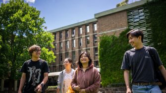 A group of four students chatting while they walk across Library Lawn on Kensington Campus