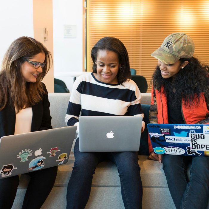 Three people sitting on sofa with MacBooks