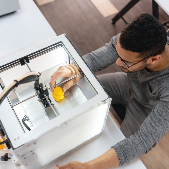 Portrait of an engineering student using a 3D printer at a workshop