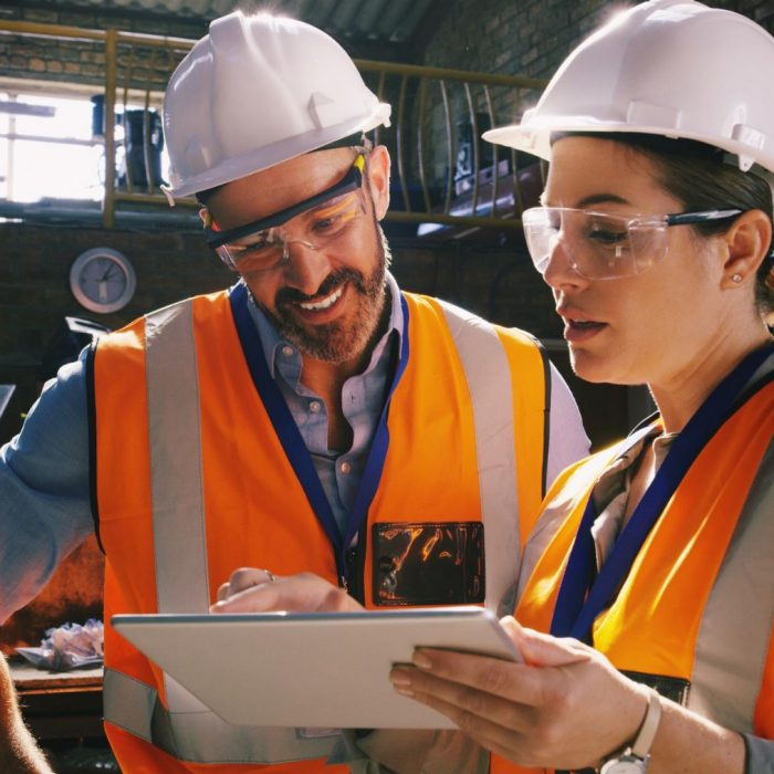 Man and woman wearing hard hats and high vis