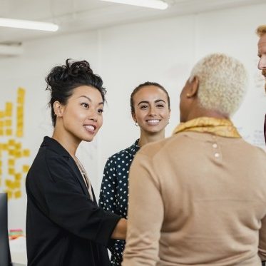 Colleagues standing in a small group discussing something while working at an office.