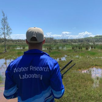 WRL researcher with a logo of Water Research Laboratory on his jacket amongst a wetland