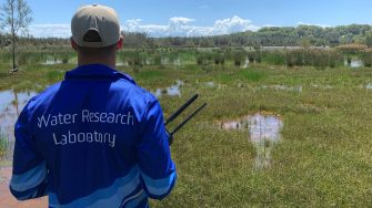 WRL researcher with a logo of Water Research Laboratory on his jacket amongst a wetland