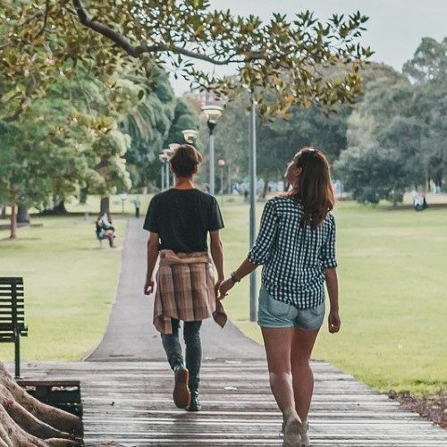 Students walk beneath tree on campus