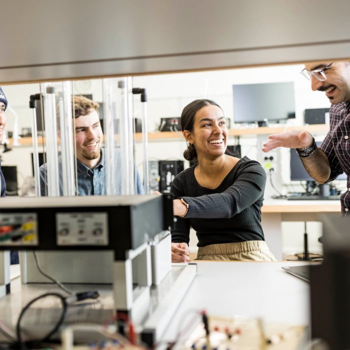 Electrical engineering students in discussion with a teacher