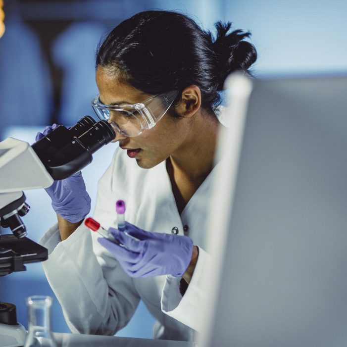 Biomedical engineer looking through a microscope in a lab