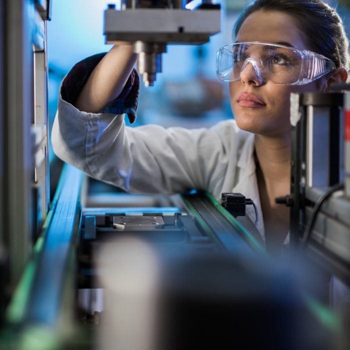 Quality control worker analyzing machine part on a manufacturing machine.