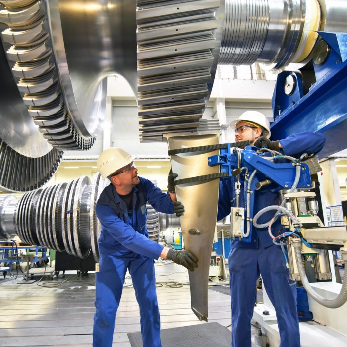 workers assembling and constructing gas turbines in a modern industrial factory