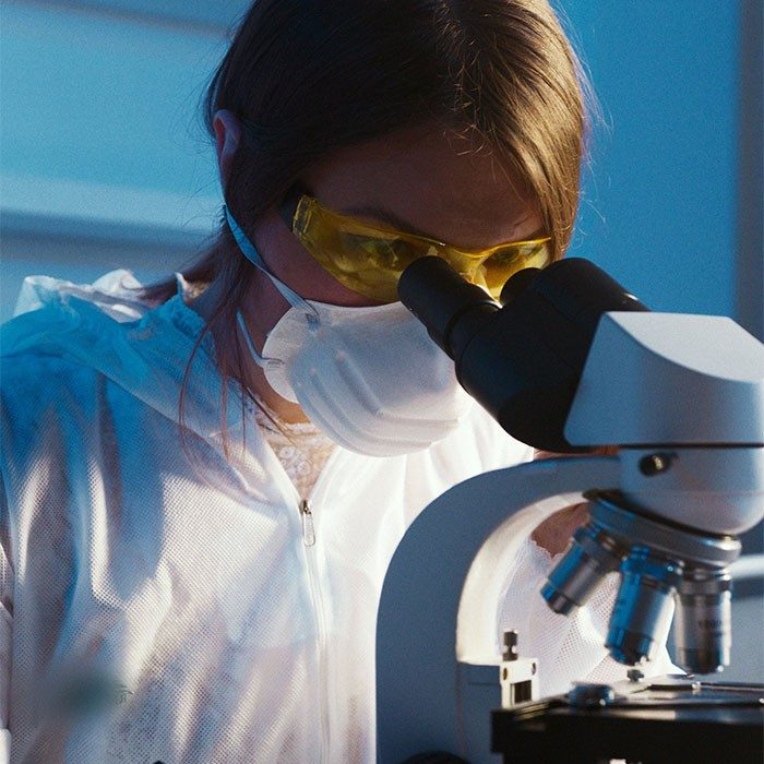 woman looking through microscope