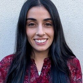 A headshot of Ella Werman smiling against a white wall