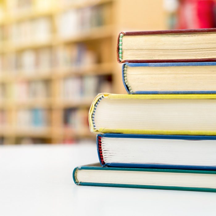 Stack and pile of books on table in public or school library.