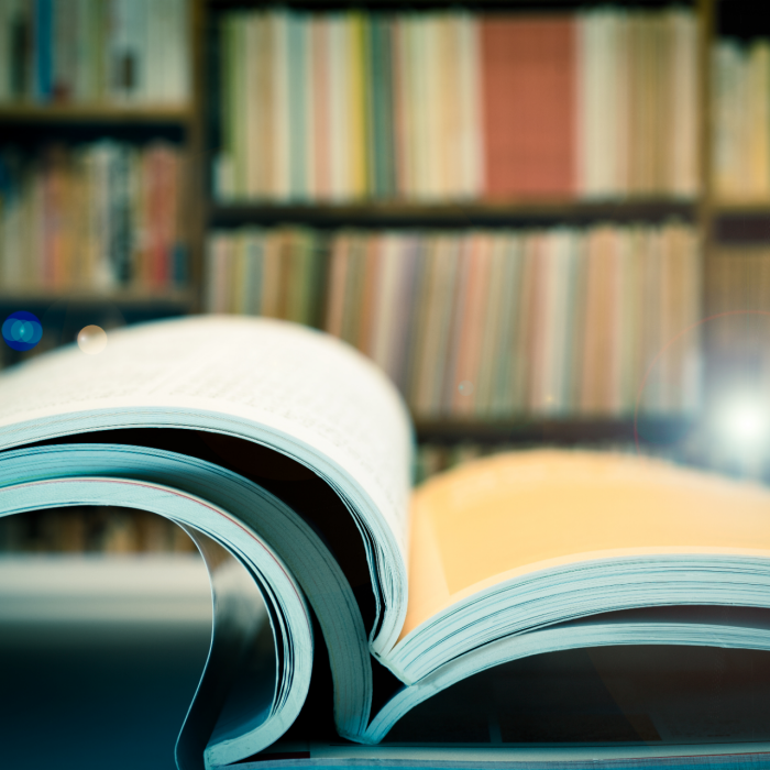 Piles of books and magazines on background of book shelf, with lens flare