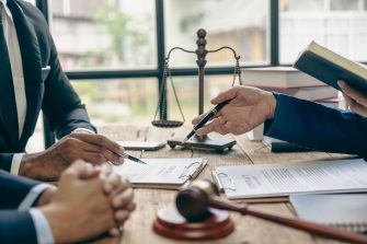 Lawyer working with client discussing contract documents with legal brass in consulting office to help client, close-up photo