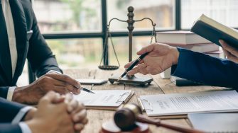 Lawyer working with client discussing contract documents with legal brass in consulting office to help client, close-up photo